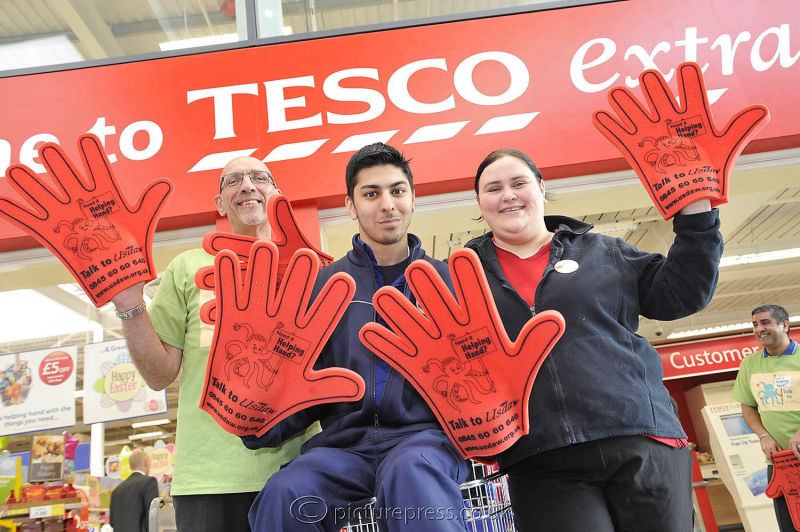 tesco supermarket staff wearing large red gloves outside tesco store.  image produced for employee magazine feature by picturepress  photography